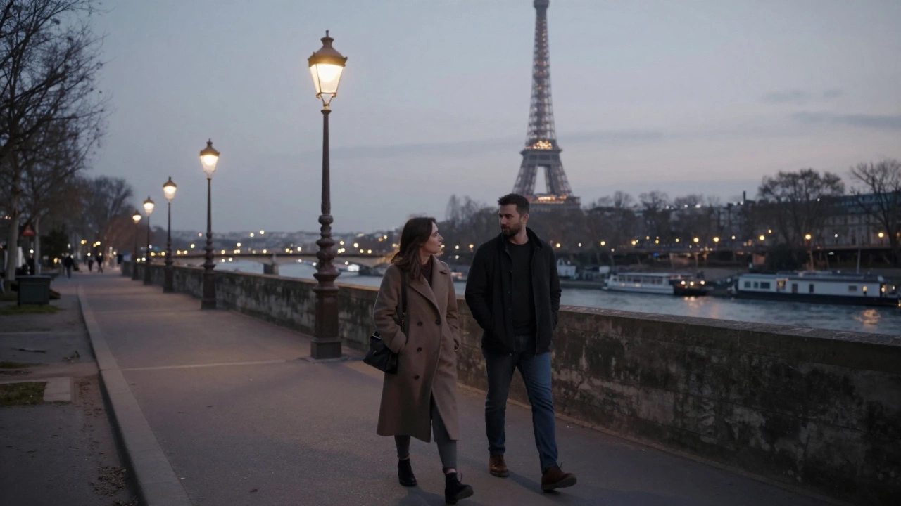 A couple walking peacefully along the Seine River at dusk, talking naturally under streetlights.